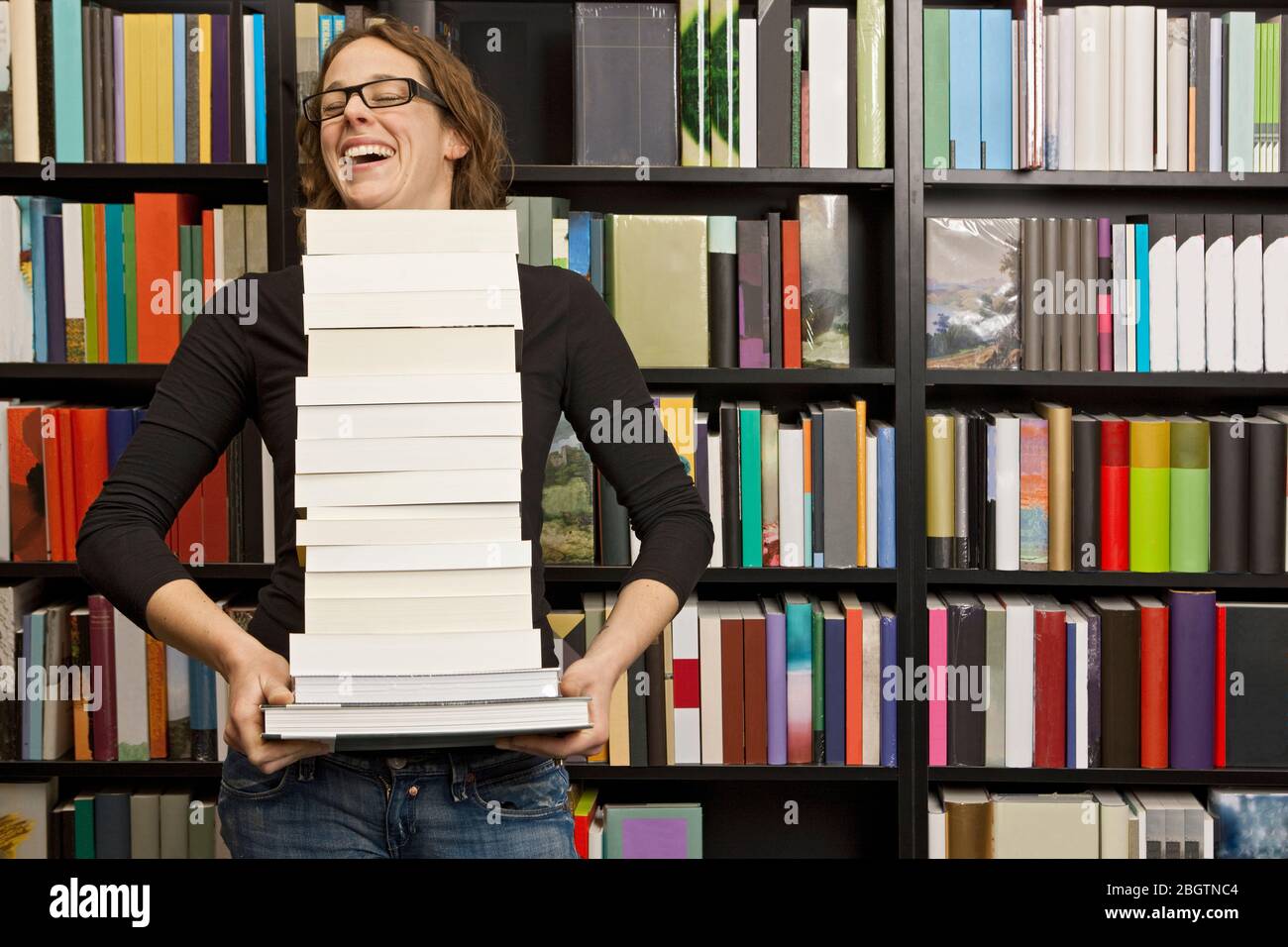 woman carrying stack of books in bookstore Stock Photo