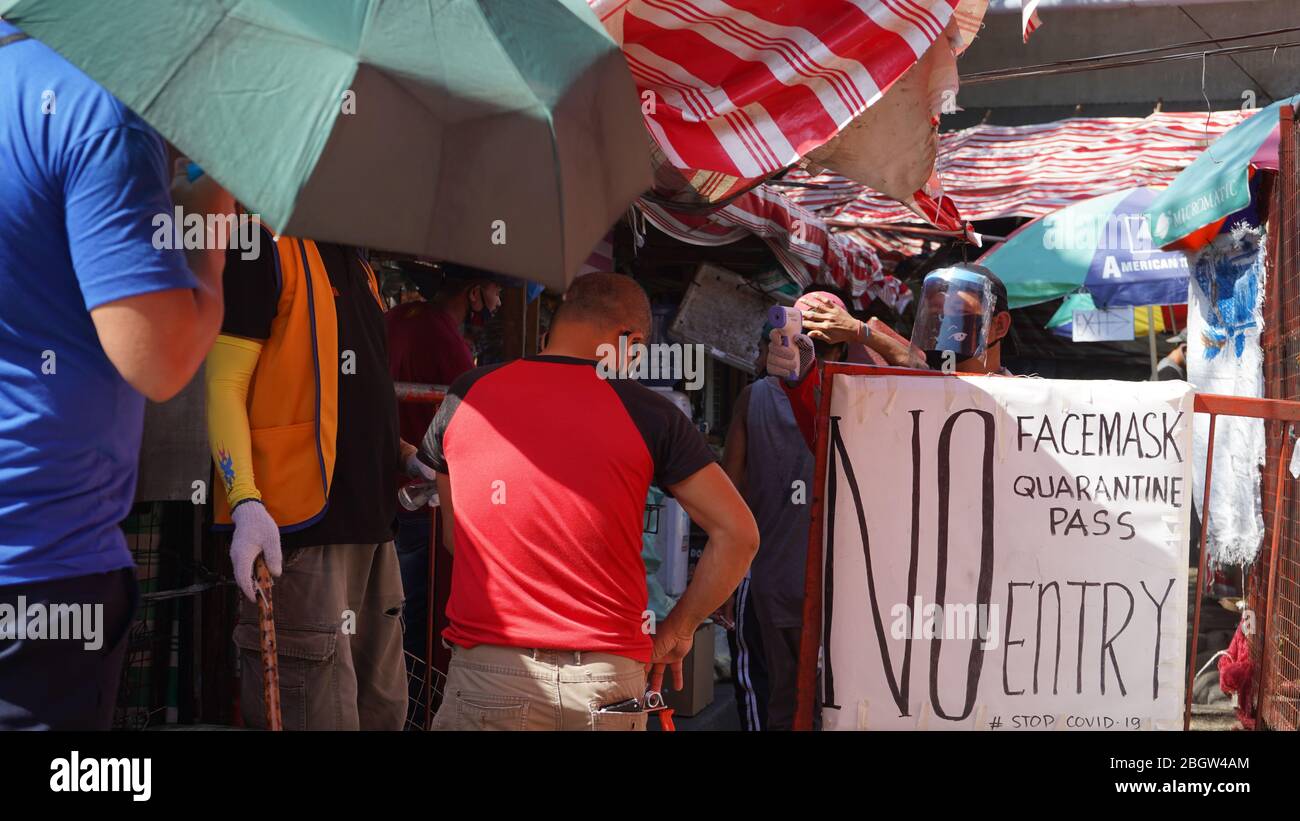 Quezon City, Philippines. 22nd Apr, 2020. Barangay officials checking the  temperature of people entering the wet market to buy daily supplies of  food, and 'no mask, no entry' policy. (Photo by Sherbien