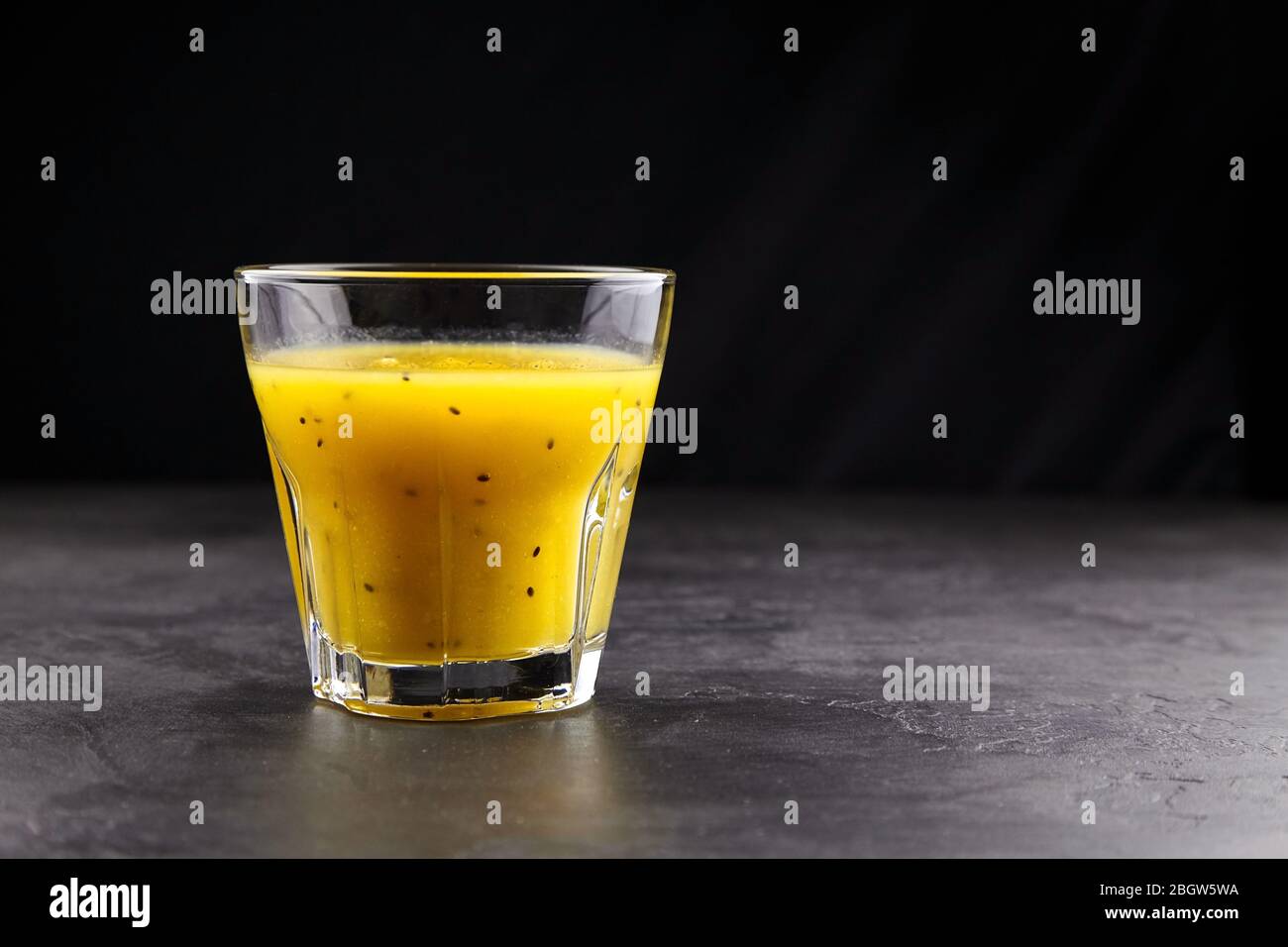 Kiwi gold fruit juice in transparent glass on stone table on black background with copy space. Fresh yellow kiwi smoothie. Healthy drink Stock Photo