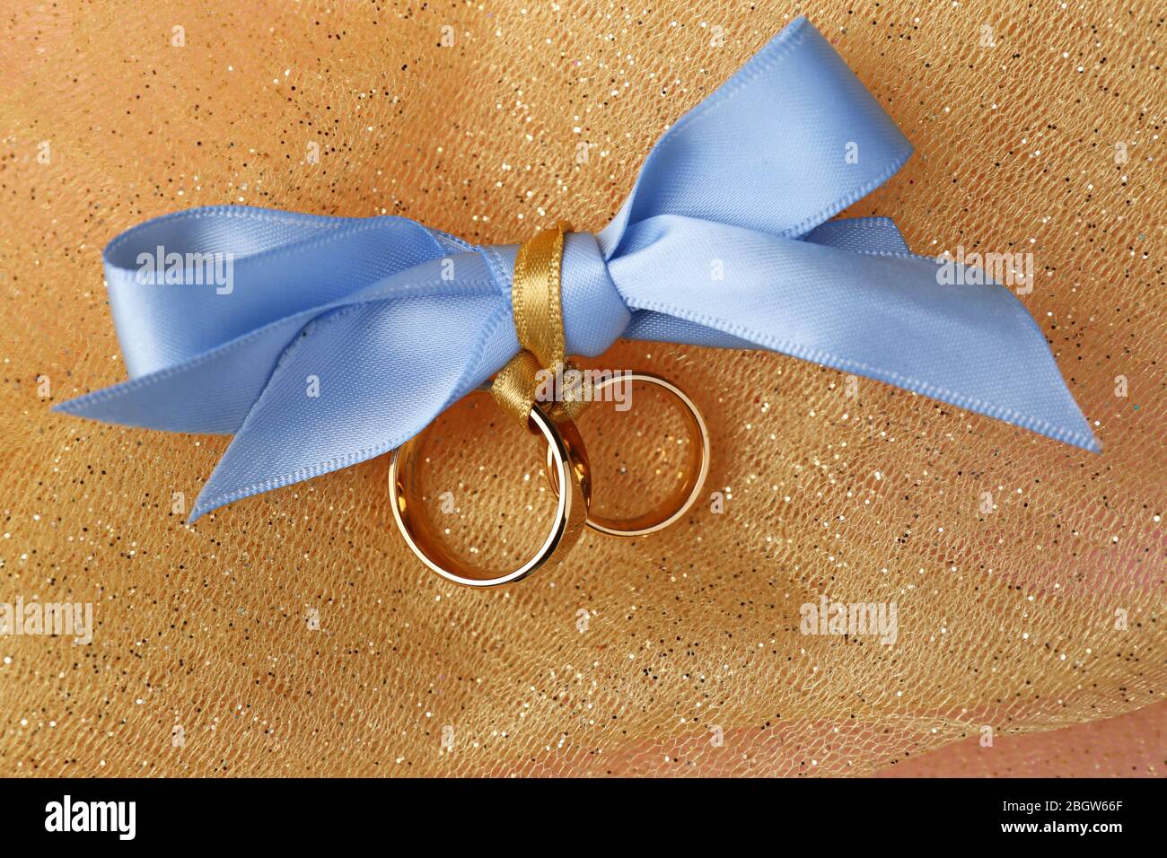 Wedding rings tied with ribbon on color fabric background Stock Photo ...