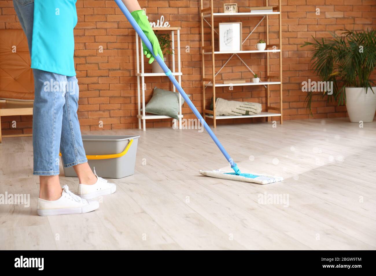 Young woman mopping floor in room Stock Photo