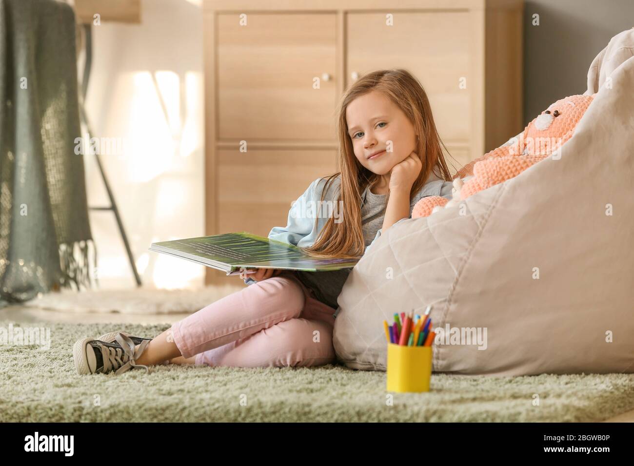 Cute little girl reading book at home Stock Photo - Alamy