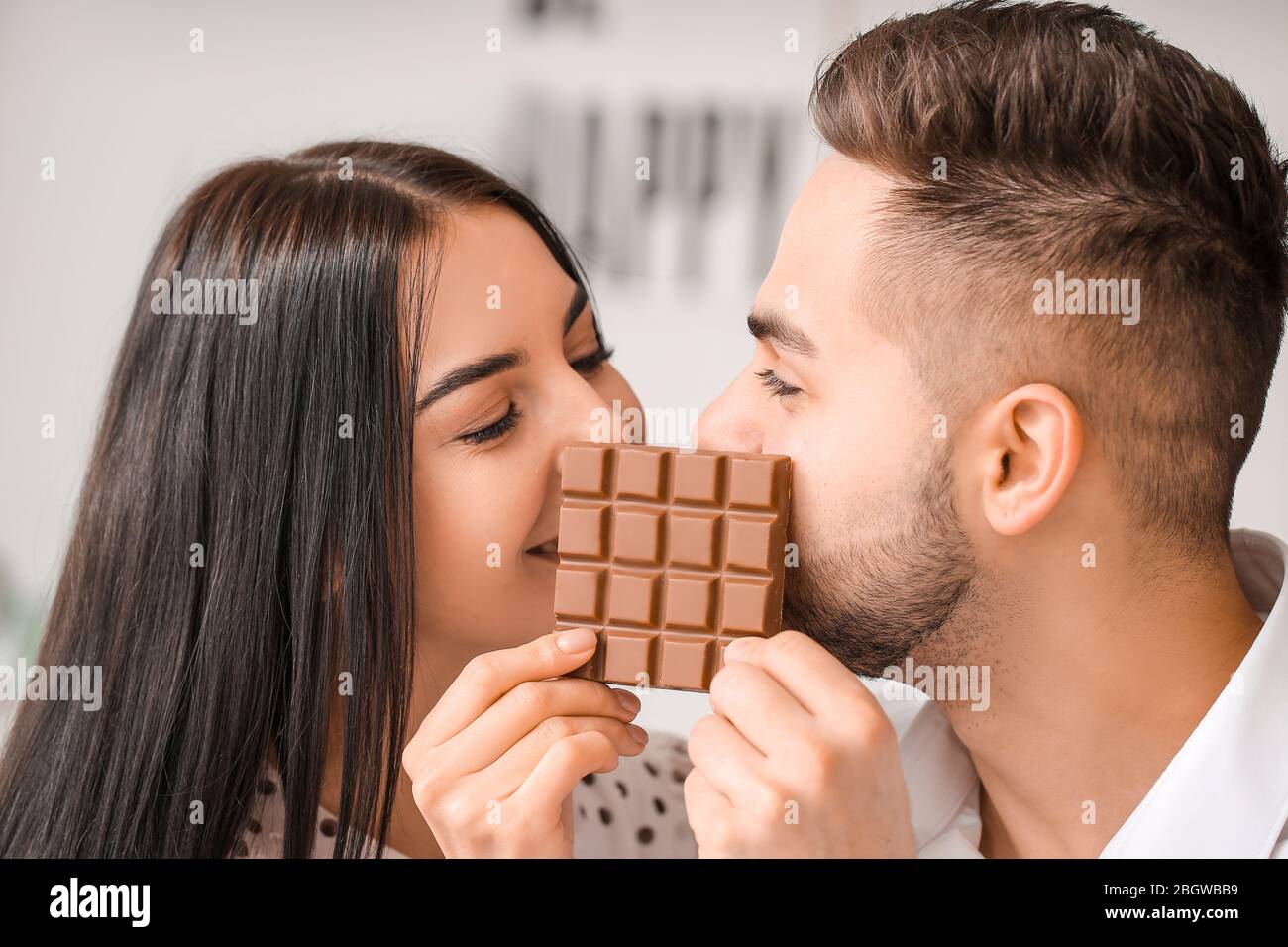 Beautiful young couple eating chocolate at home Stock Photo - Alamy
