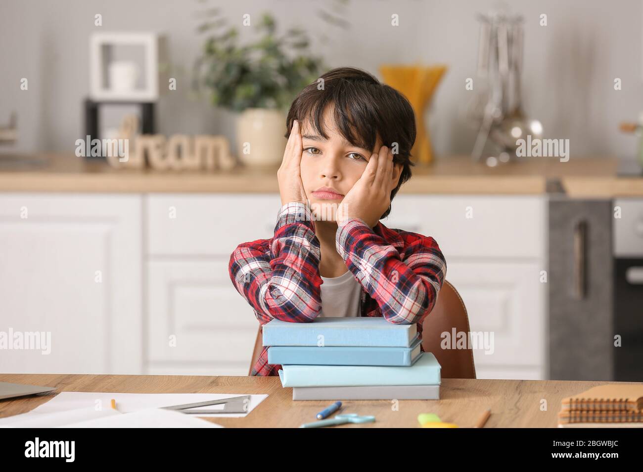 Little boy tired of doing homework in kitchen Stock Photo - Alamy