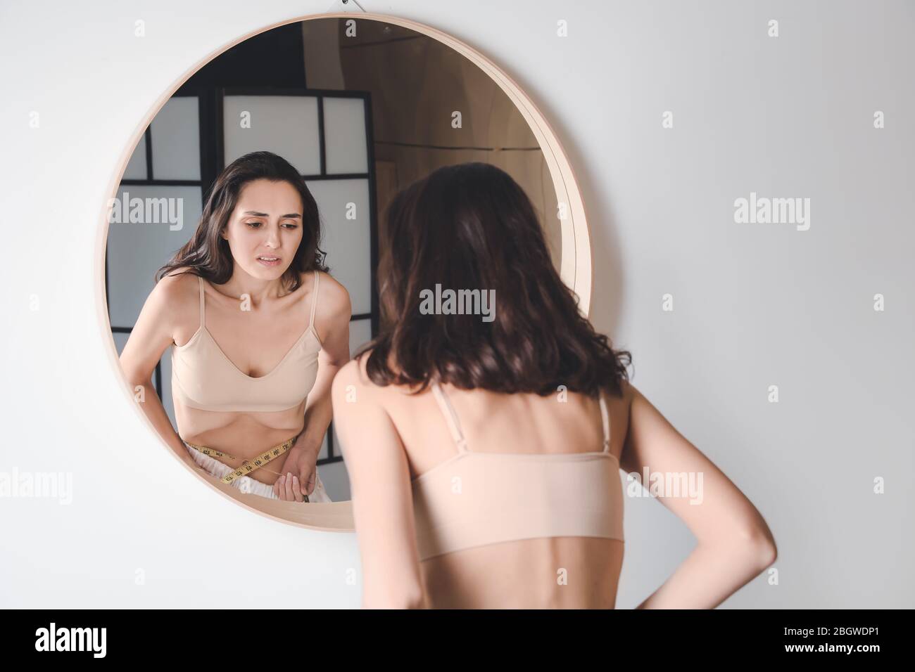 Young woman with anorexia near mirror at home Stock Photo