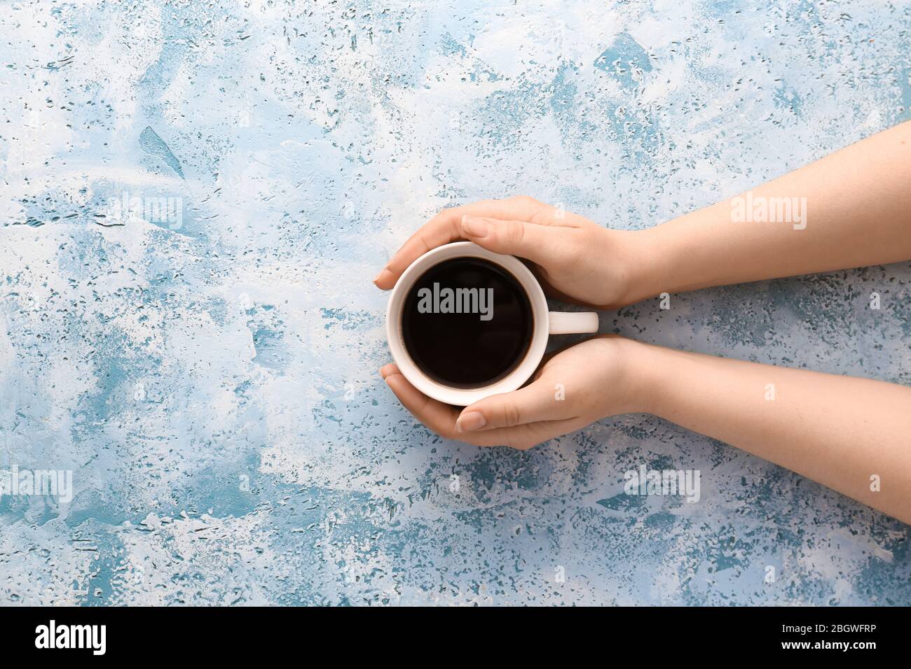 Female hands with cup of hot coffee on color background, top view Stock Photo - Alamy