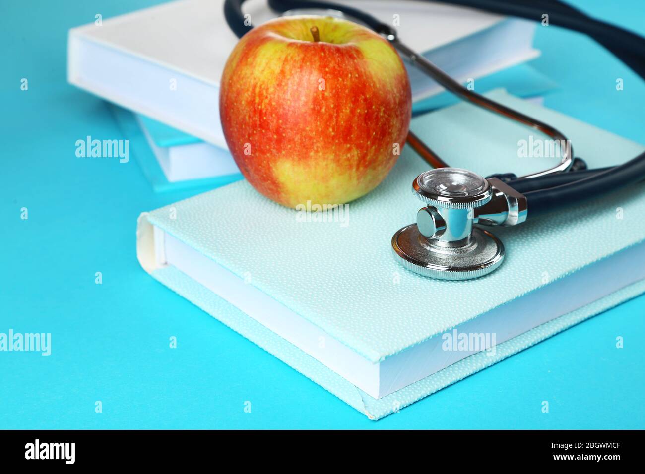 Medical stethoscope with apple and books on blue background Stock Photo ...
