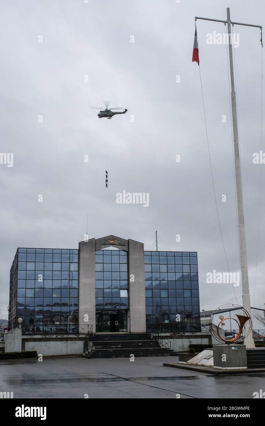 ANNECY, FRANCE - FEBRUARY 23: French soldiers from the 27th Alpine Fighter Regiment hanging on a rope from a land force helicopter above a building du Stock Photo