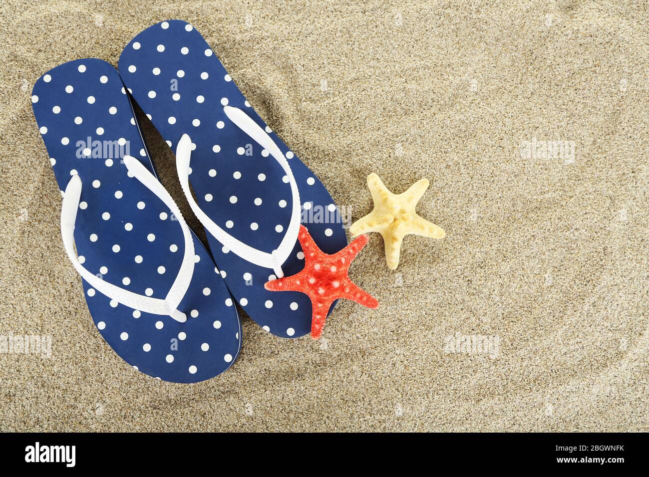 Flip flops on sea sand background Stock Photo - Alamy