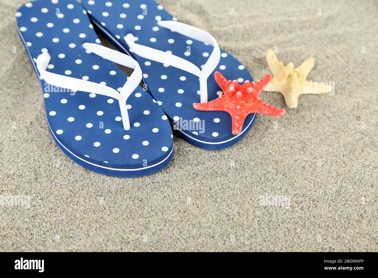 Flip flops on sea sand background Stock Photo - Alamy