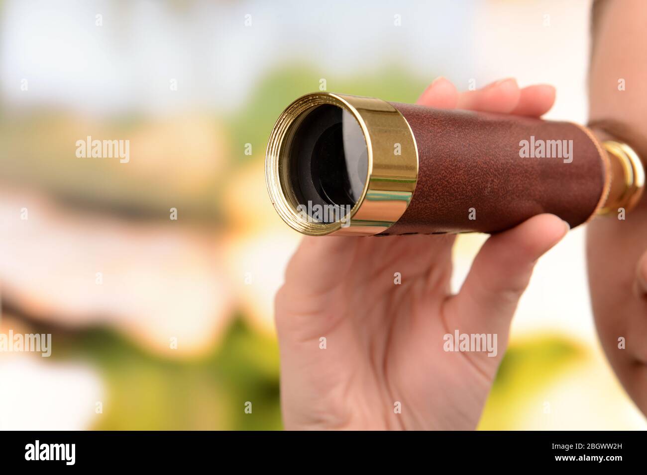 Modern spyglass in hands on bright background Stock Photo - Alamy