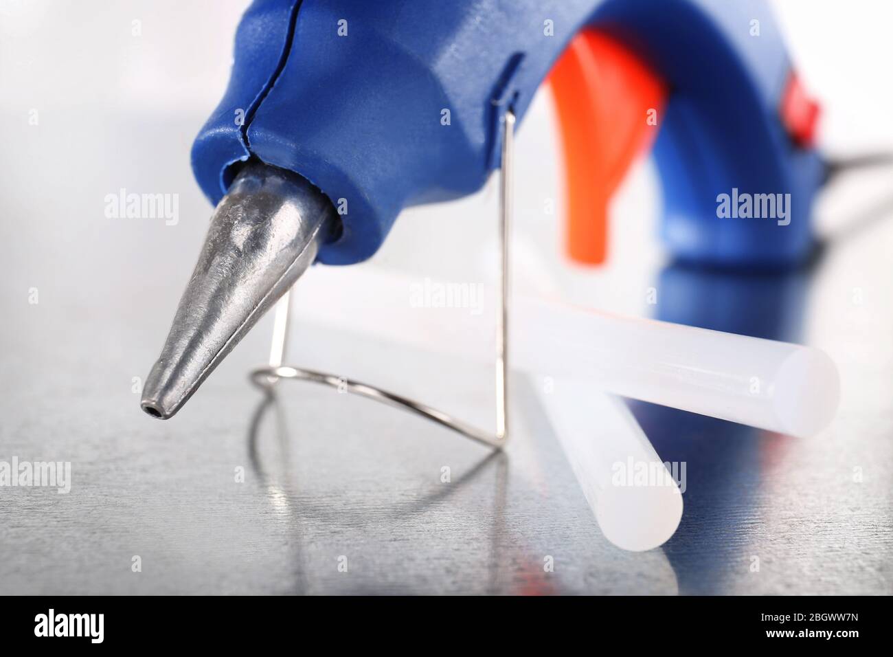 Dark blue glue gun and silicone stick on light background Stock Photo
