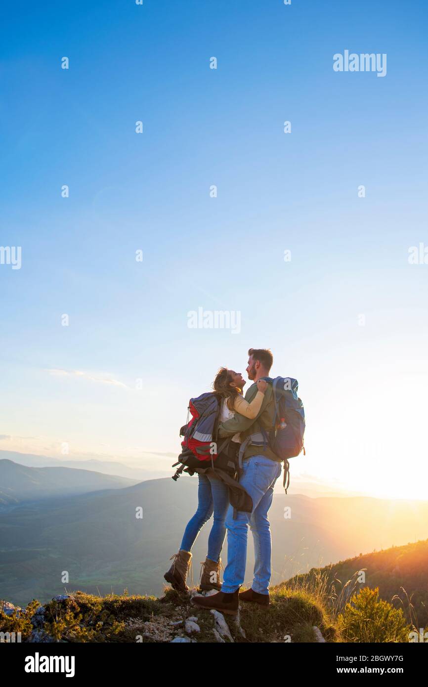 Hikers with backpacks relaxing on top of a mountain and enjoying the ...