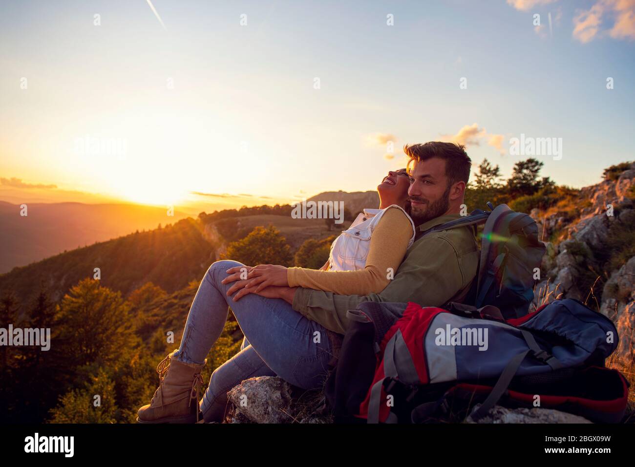 Couple Man and Woman sitting on cliff enjoying mountains and clouds ...