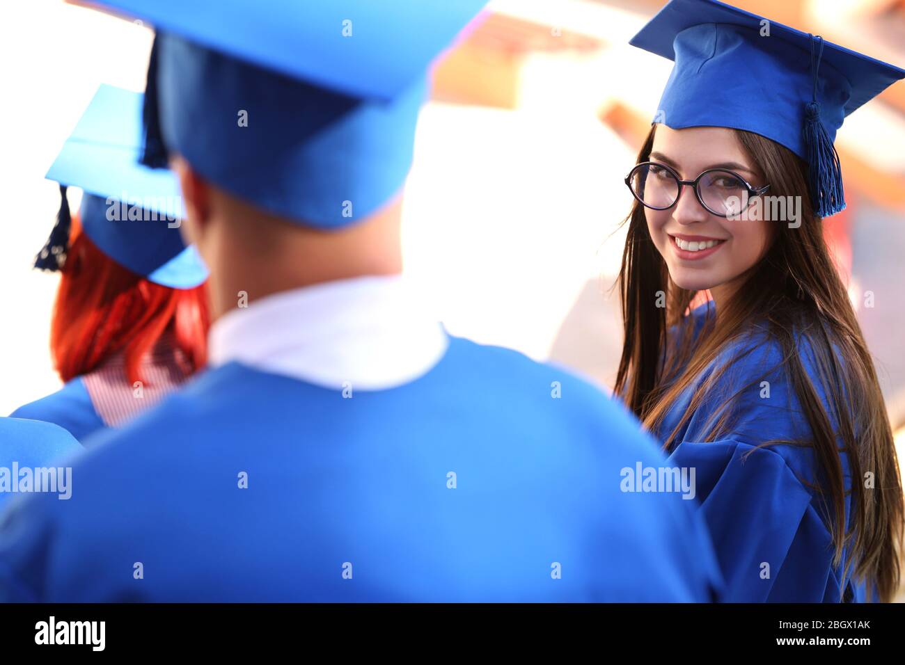 Graduate students wearing graduation hat and gown, outdoors Stock Photo
