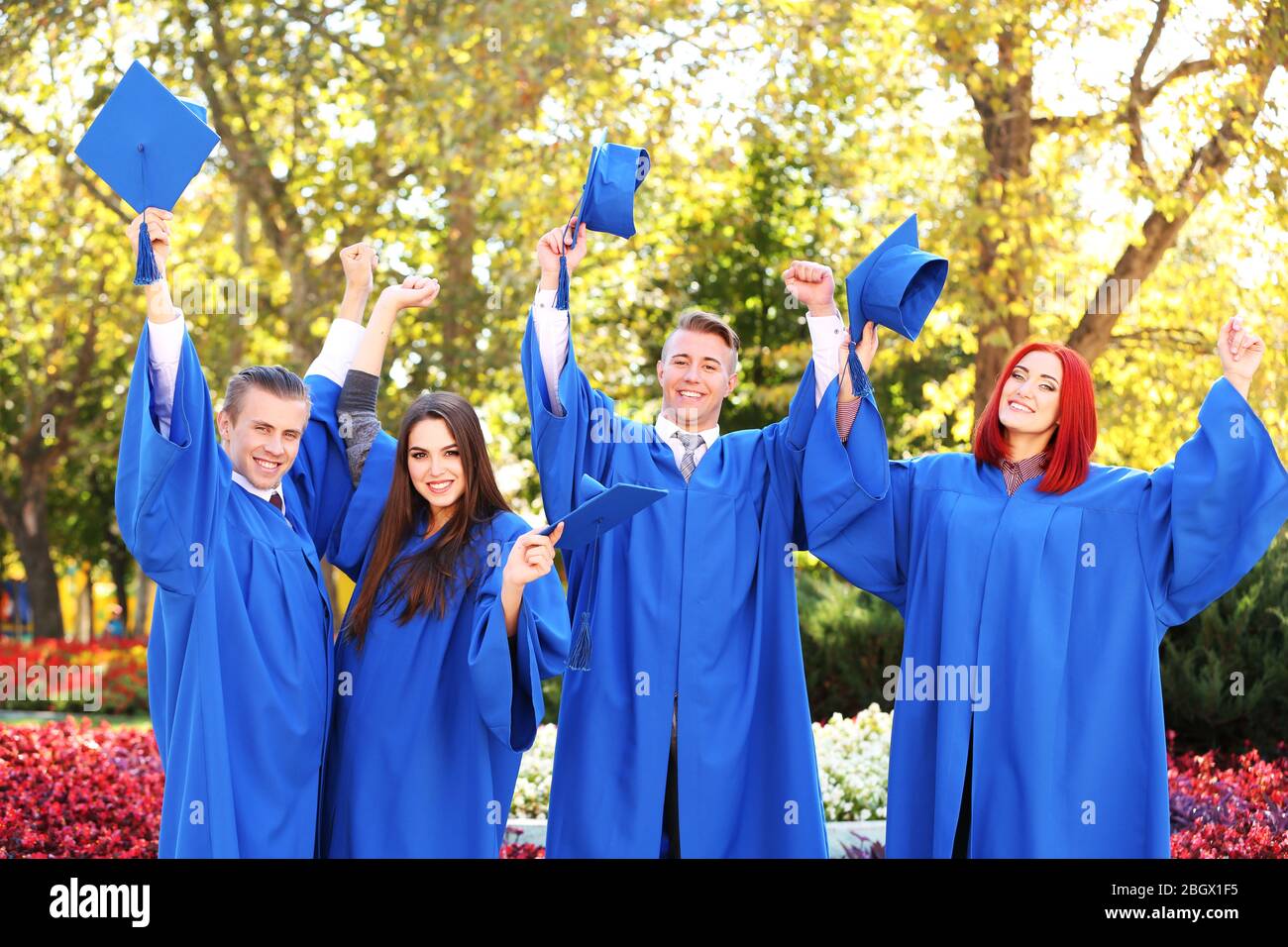 Graduate students throwing graduation hats in the air, outdoors Stock ...