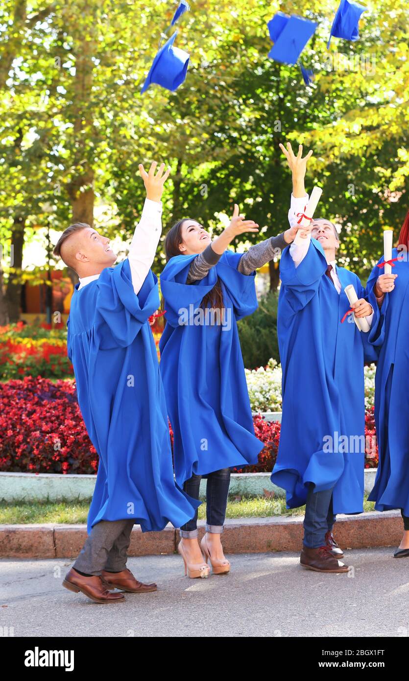 Students throwing graduation hats in air, outdoors Stock Photo Alamy