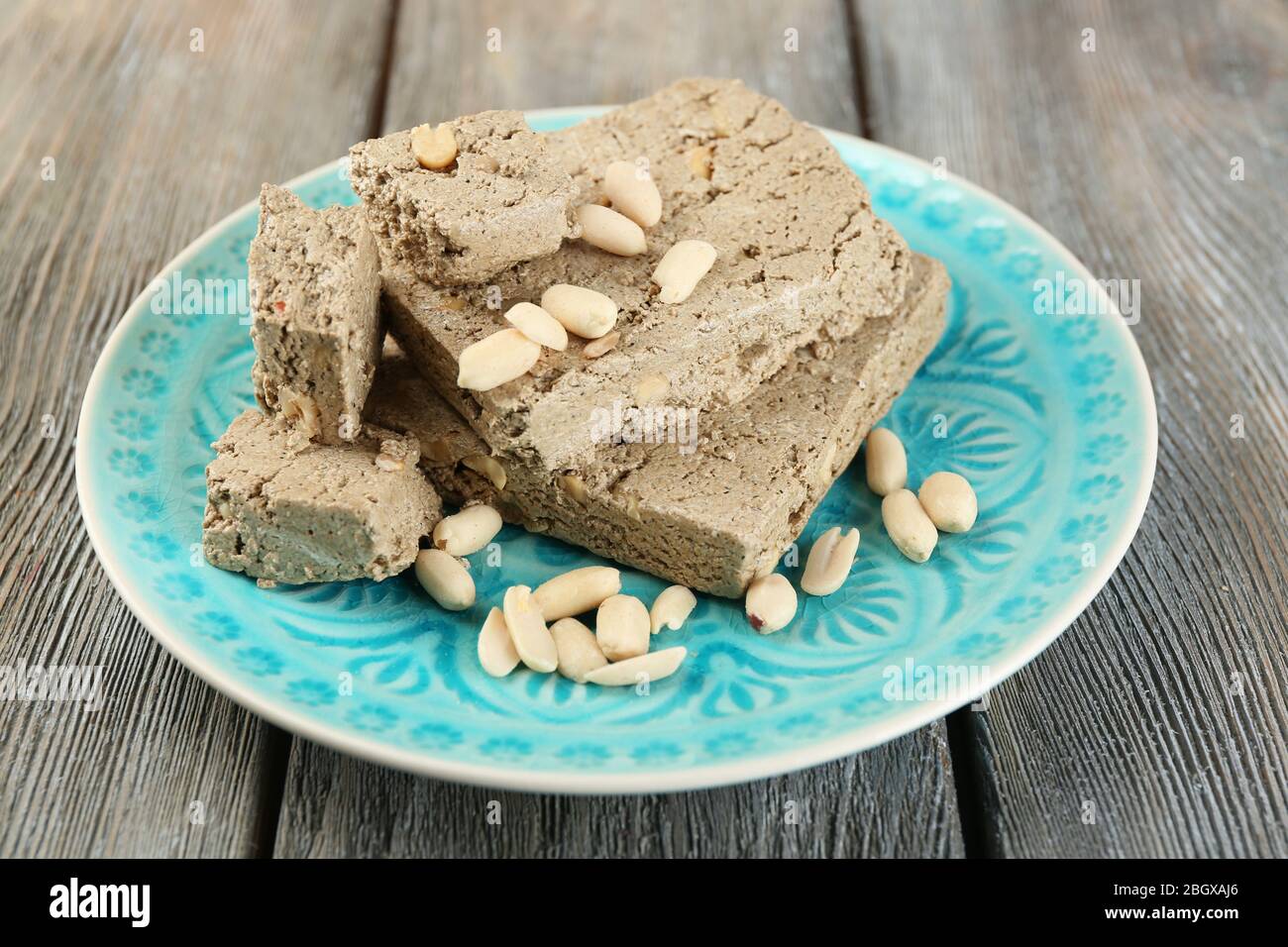 Sunflower halva with peanuts on plate, on wooden background Stock Photo