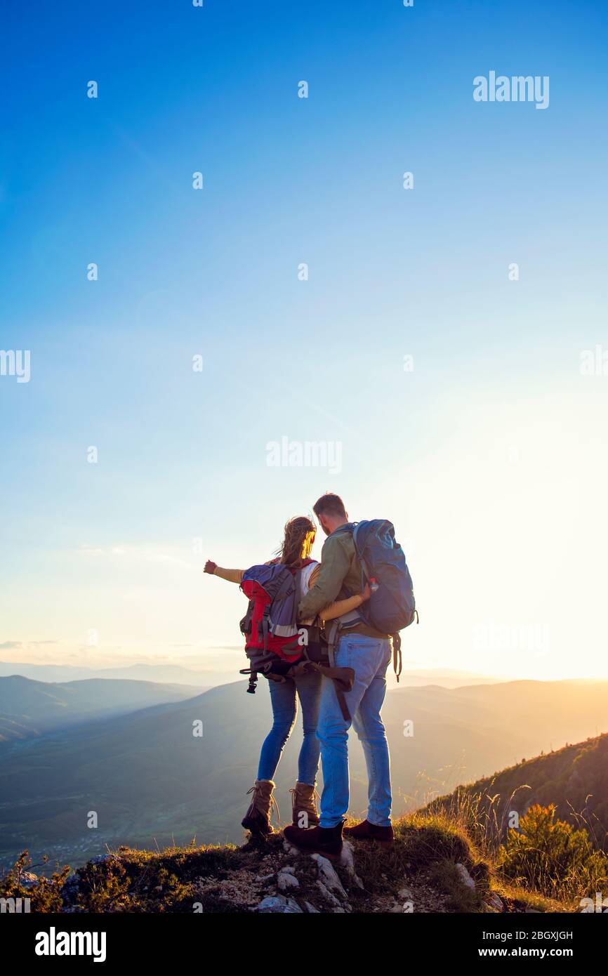 Hikers with backpacks relaxing on top of a mountain and enjoying the ...