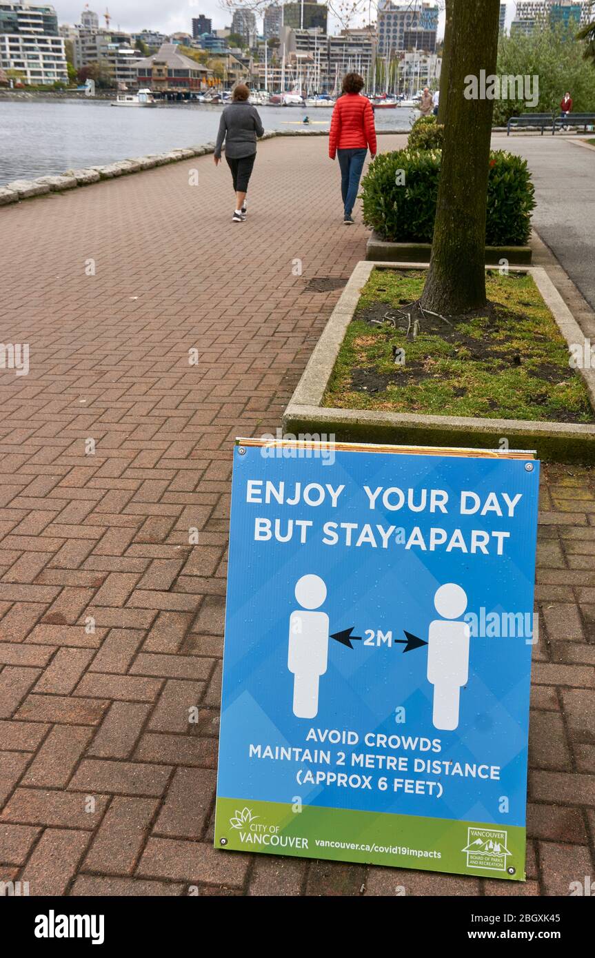 Vancouver, Canada, 22 April 2020. A sign on a footpath reminds people to follow social distancing rules and stay two metres (six feet) apart from each other during the COVD-19 pandemic. Stock Photo