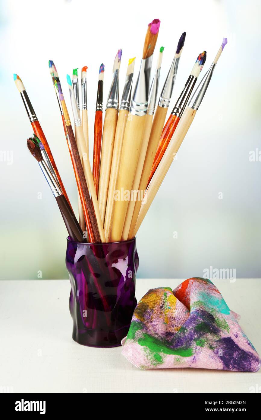 Paint brushes with paints and palette on bright background Stock