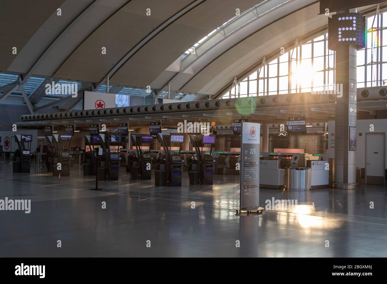 Sun shining into￼ a vacant￼ Air Canada check-in area inside Terminal 1 at Toronto Pearson Intl. Airport during the COVID-19 pandemic. Stock Photo