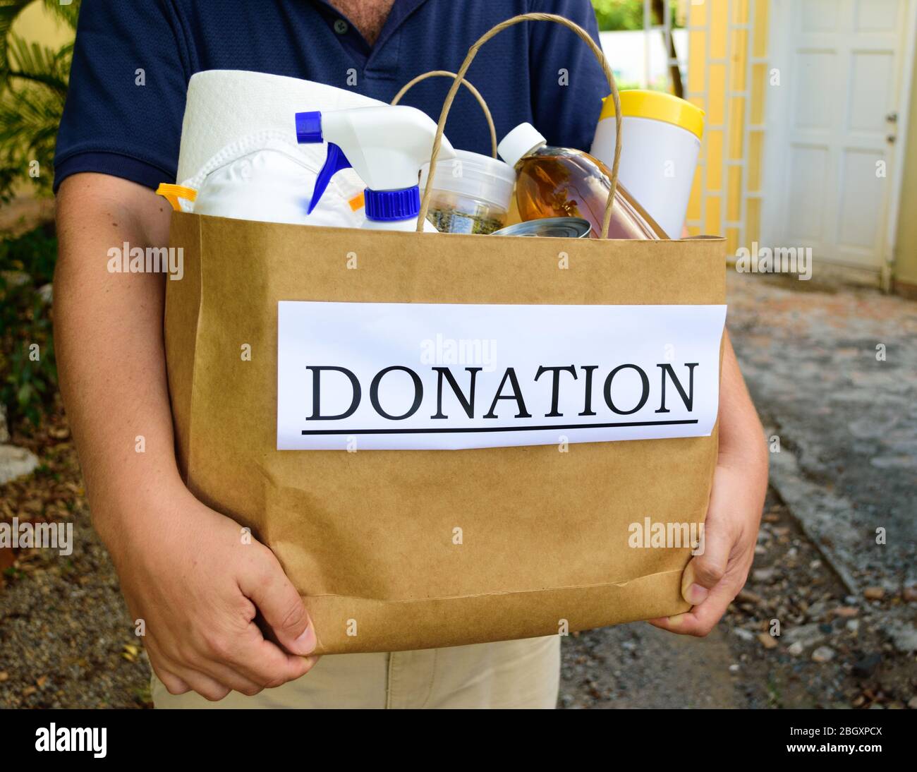 A volunteer delivers a donation bag filled with food and cleaning supplies during the Covid-19 / Coronavirus Pandemic Stock Photo