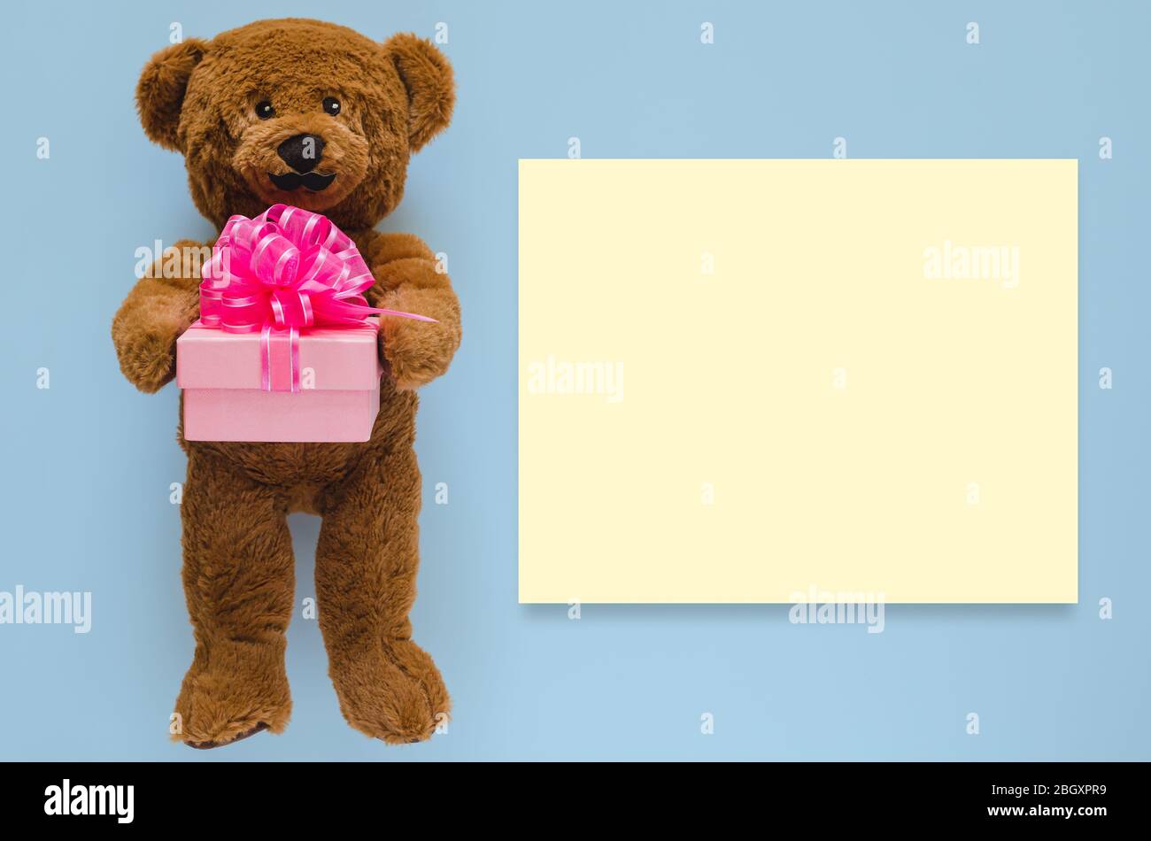 Teddy bear with mustache holding gift box with empty yellow space for text on blue background. Father day concept Stock Photo Alamy