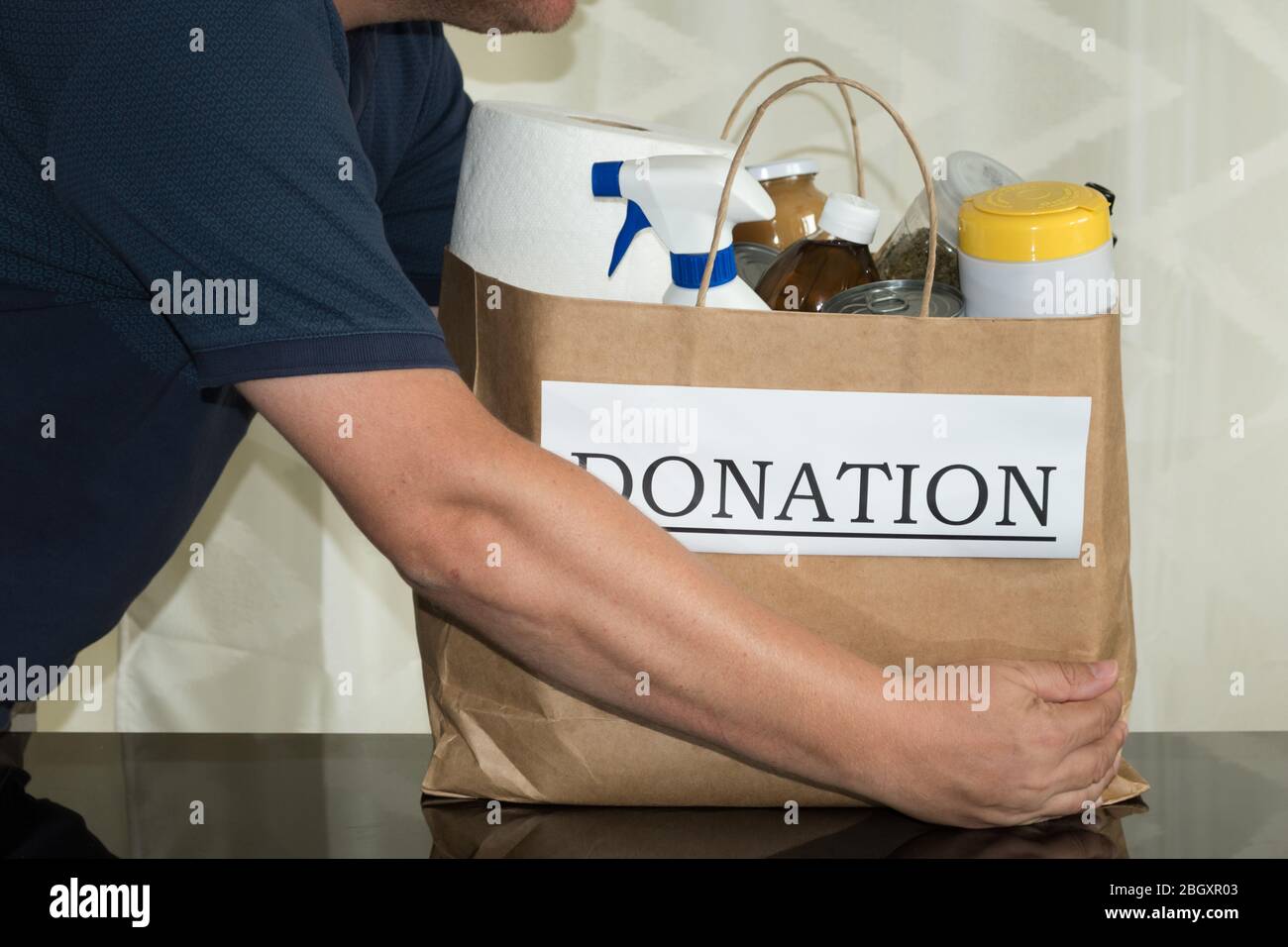 A volunteer collects a donation bag with cleaning & food supplies to be handed out to people in need during the Coronavirus / Covid-19 pandemic Stock Photo