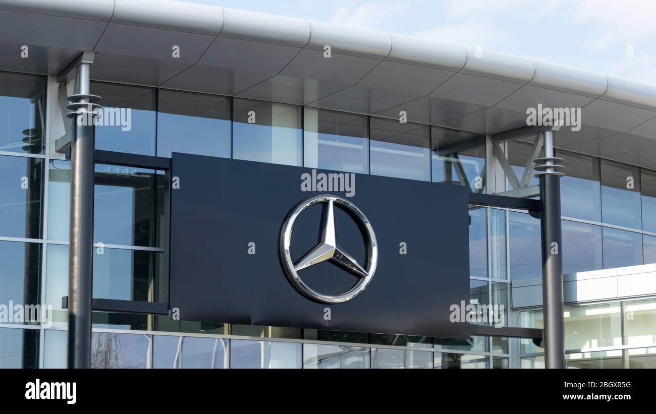 Mercedes-Benz star emblem posted on the outside of a dealership. Stock Photo
