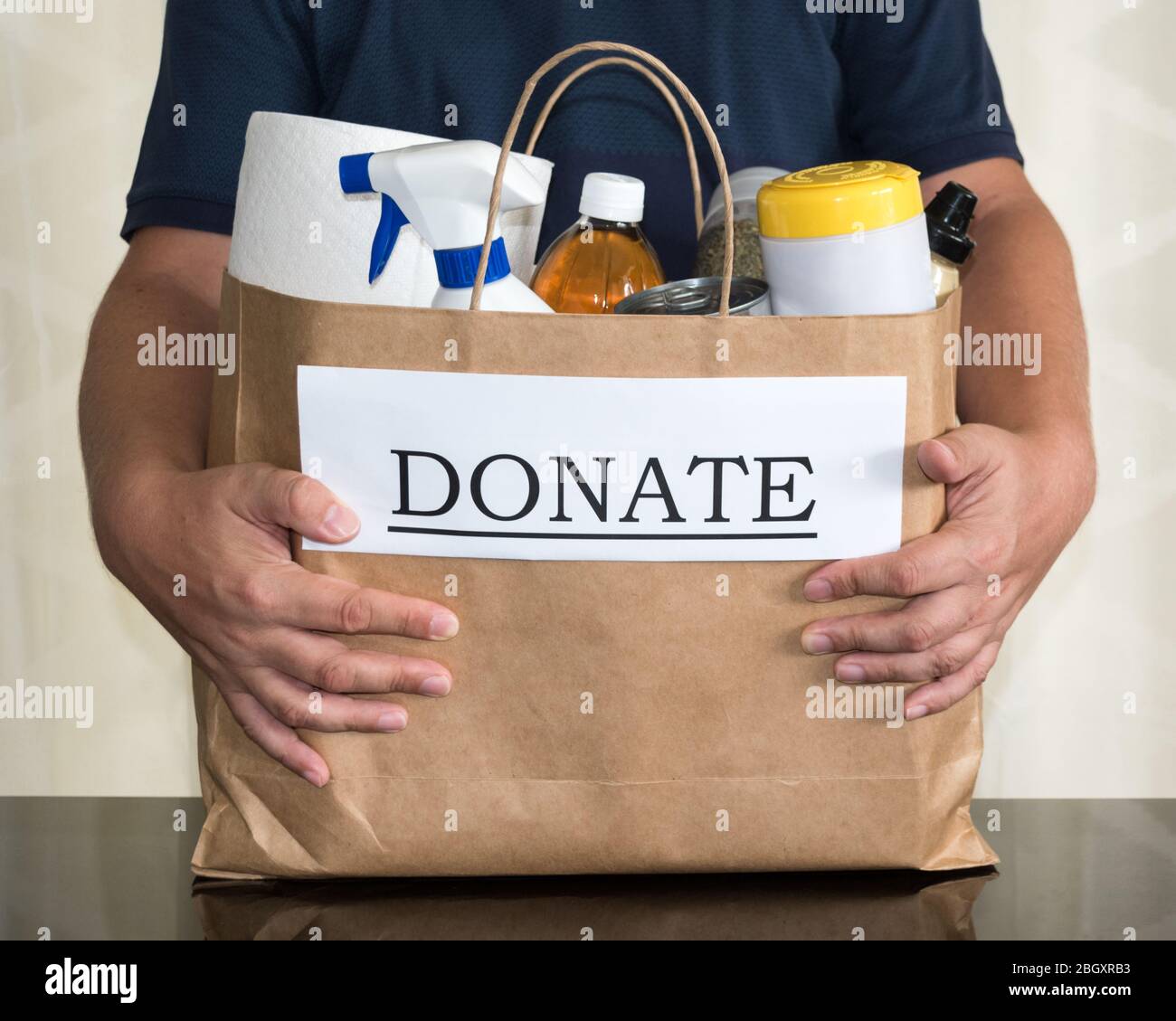 A volunteer collects a donation bag containing cleaning & food supplies to be delivered to those in need during the Coronavirus / Covid-19 Pandemic Stock Photo