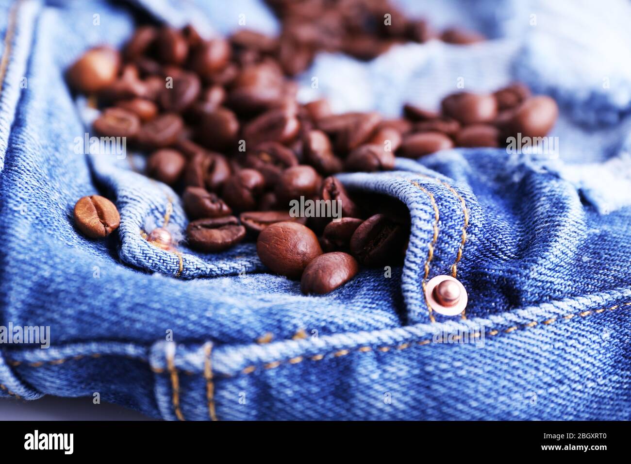 Handful of coffee beans on ripped jeans background Stock Photo - Alamy