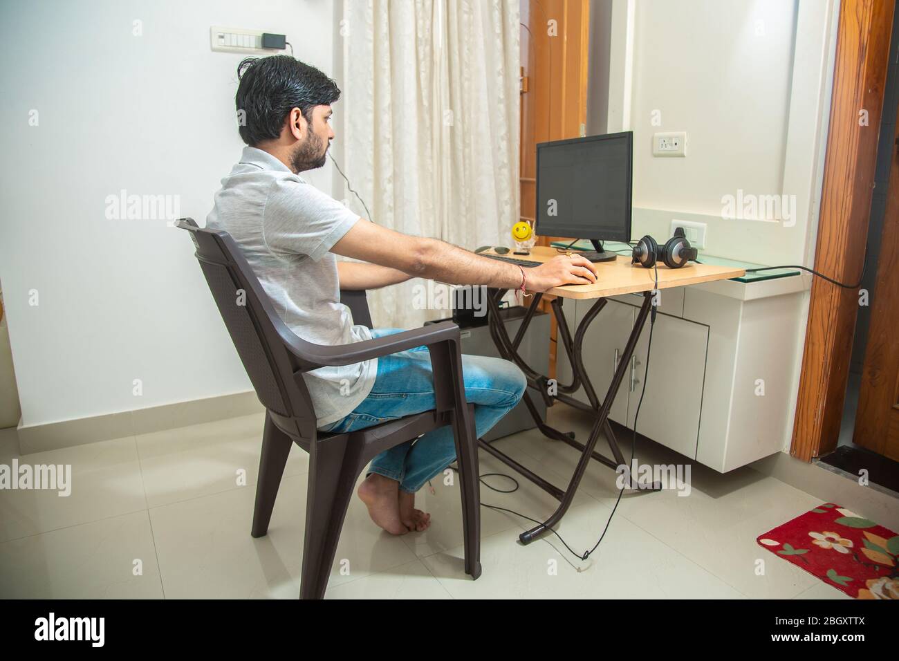 https://c8.alamy.com/comp/2BGXTTX/young-indian-man-sitting-at-a-table-at-home-working-on-a-computer-side-viewfreelancer-working-from-homeyoung-male-student-typing-on-computer-wearin-2BGXTTX.jpg