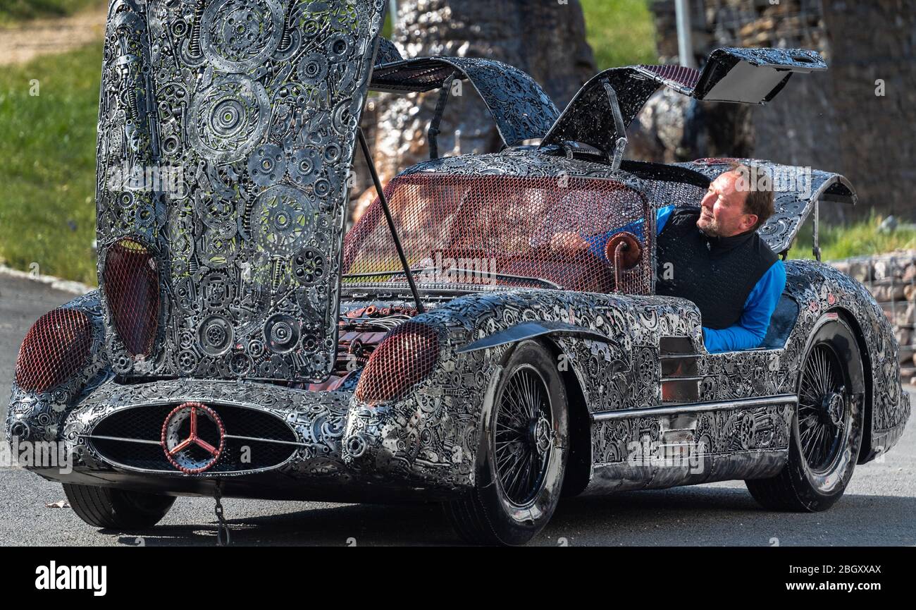 21 April 2020, Saxony, Dorfhain: Jens Jähnig, head of the charitable foundation Georado, sits on his company premises in a 'Mercedes SLR 300 Uhlenhaut Coupe', made of scrap metal. The foundation also relies on art to enhance the region. To this end, the Geoart network was created, which unites artists with the public and sculptures. For a fair, which cannot take place in its original form due to the Corona crisis, the foundation has brought parts of the 'Giants of Steel', sculptures made from thousands of individual parts of scrap metal, to Dorfhain. Photo: Robert Michael/dpa-Zentralbild/dpa Stock Photo