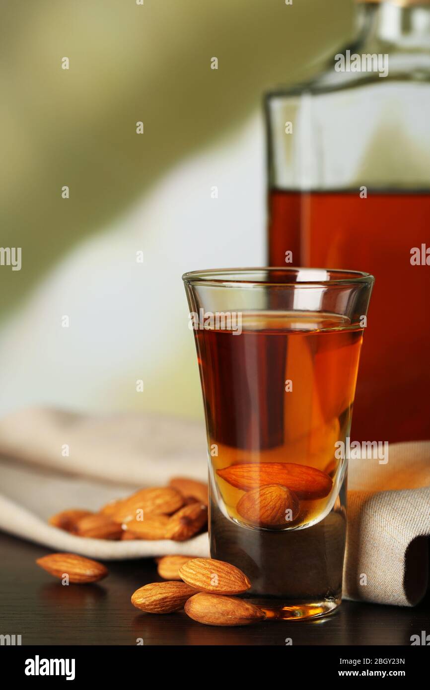 Dessert liqueur Amaretto with almond nuts, on wooden table, on light