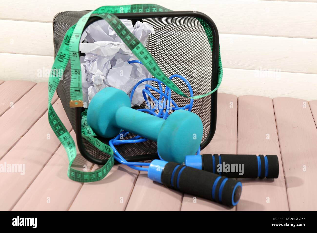 Metal trash bin with sport equipment, crumpled paper and weight scale