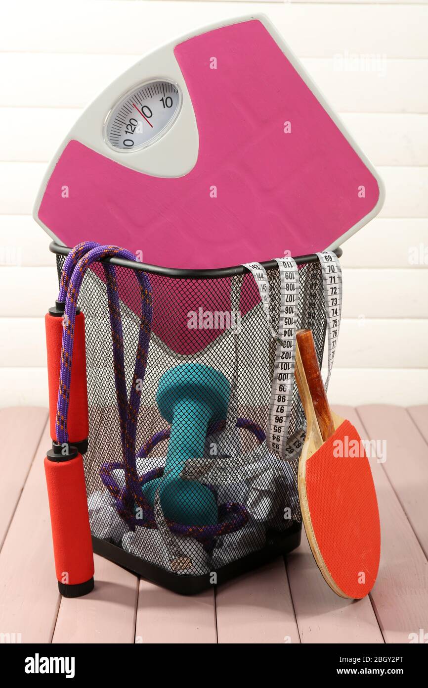 Metal trash bin with sport equipment, crumpled paper and weight scale