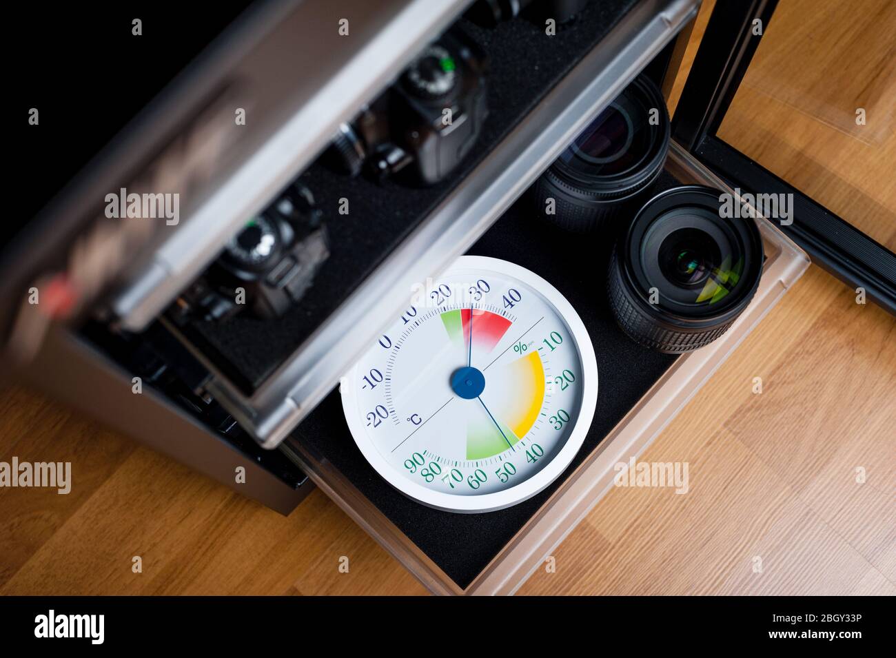 white analog Thermometer and Hygrometer with photography equipments. Lenses and camera equipment