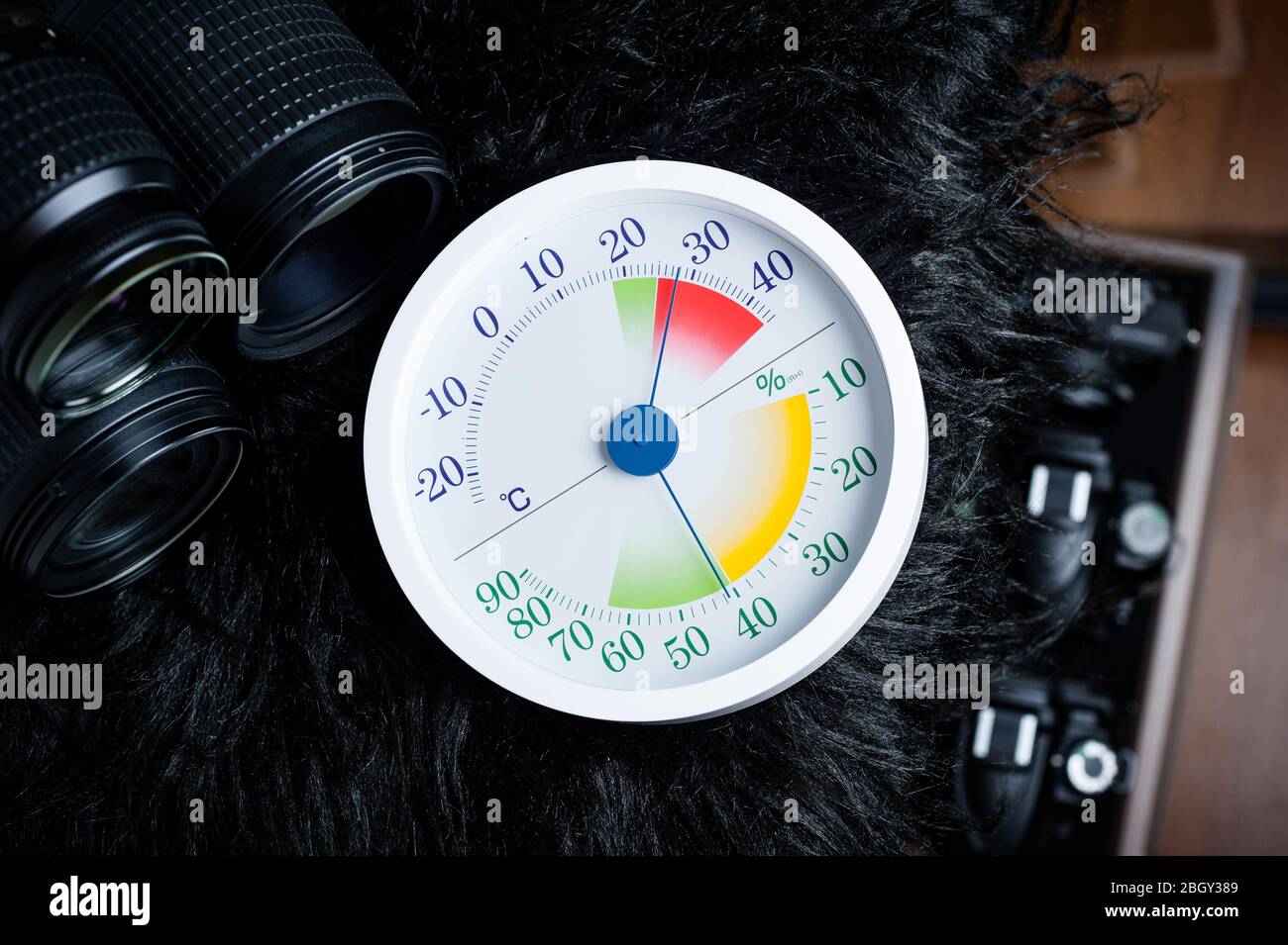 white analog Thermometer and Hygrometer with photography equipments. Lenses and camera equipment are optimally stored at a relative humidity (RH) of a Stock Photo