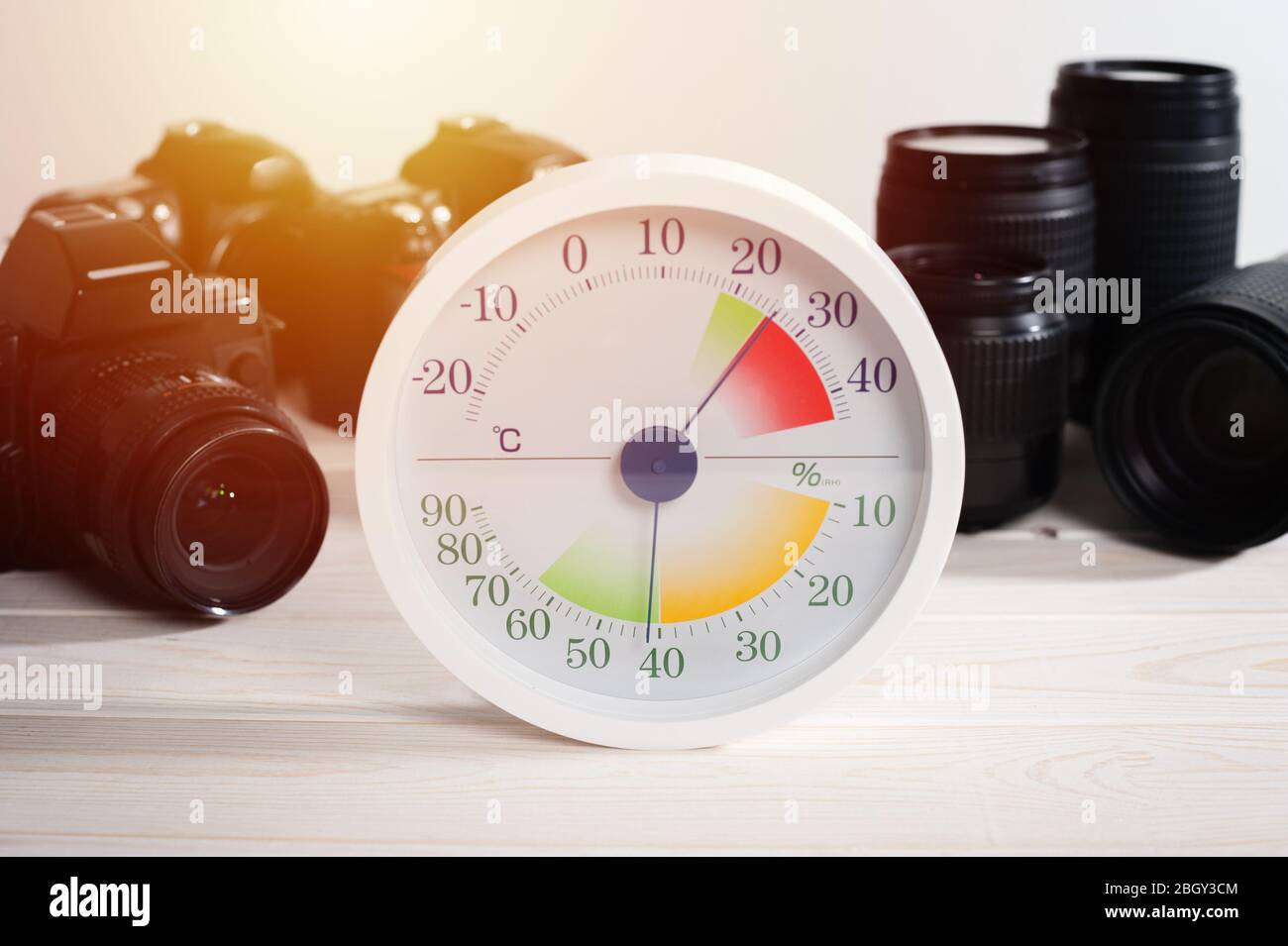 white analog Thermometer and Hygrometer with photography equipments. Lenses and camera equipment