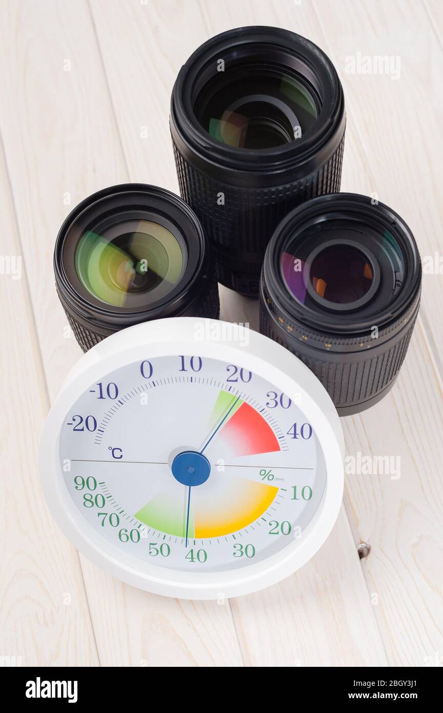 white analog Thermometer and Hygrometer with photography equipments. Lenses and camera equipment