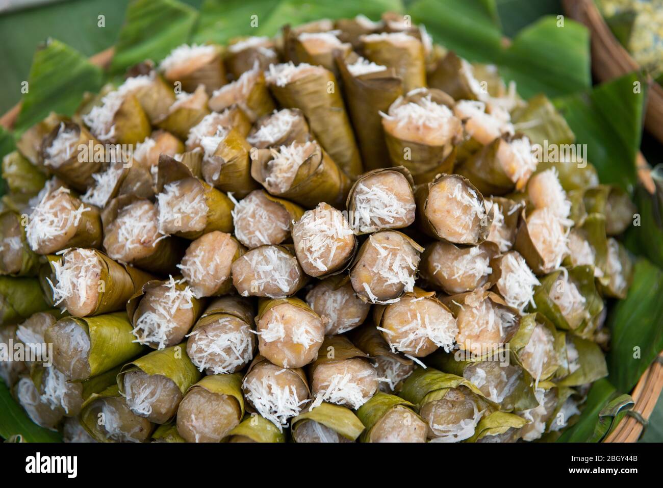 Thai traditional dessert, Steamed banana cake in funnel banana leaves at street market in Thailand Stock Photo