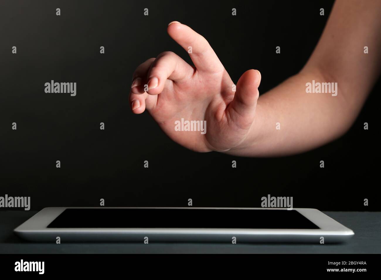 Hand using tablet PC on table and dark background Stock Photo - Alamy