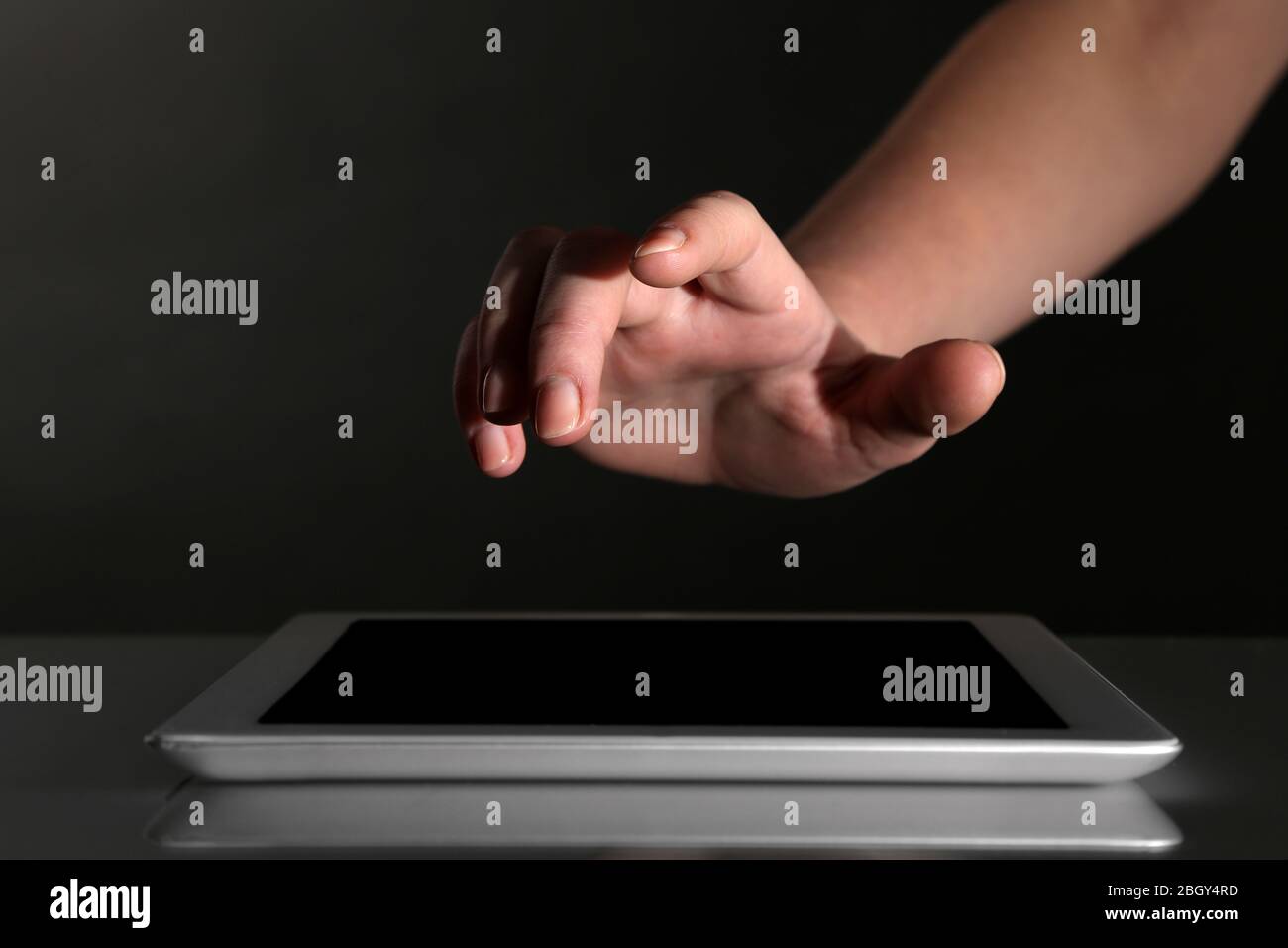 Hand using tablet PC on table and dark background Stock Photo - Alamy