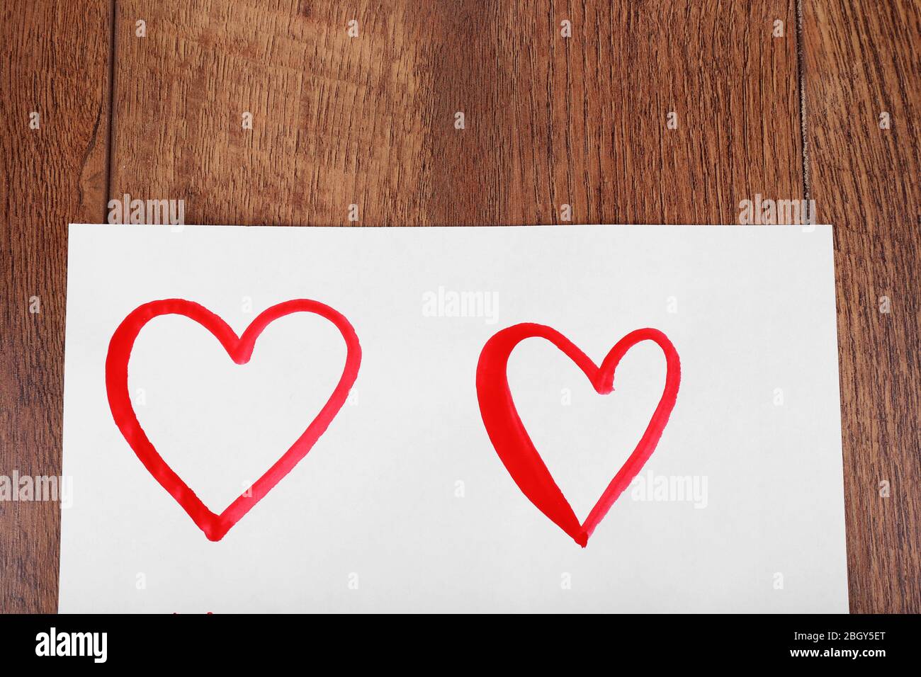 Painted hearts on sheet of paper on wooden table background Stock Photo ...