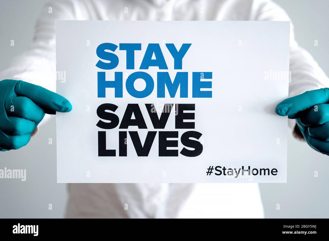 Doctor holding a sign saying 'Stay Home Save Lifes' global message for the coronavirus crisis. Quarantine message across the globe to fight COVID-19 Stock Photo
