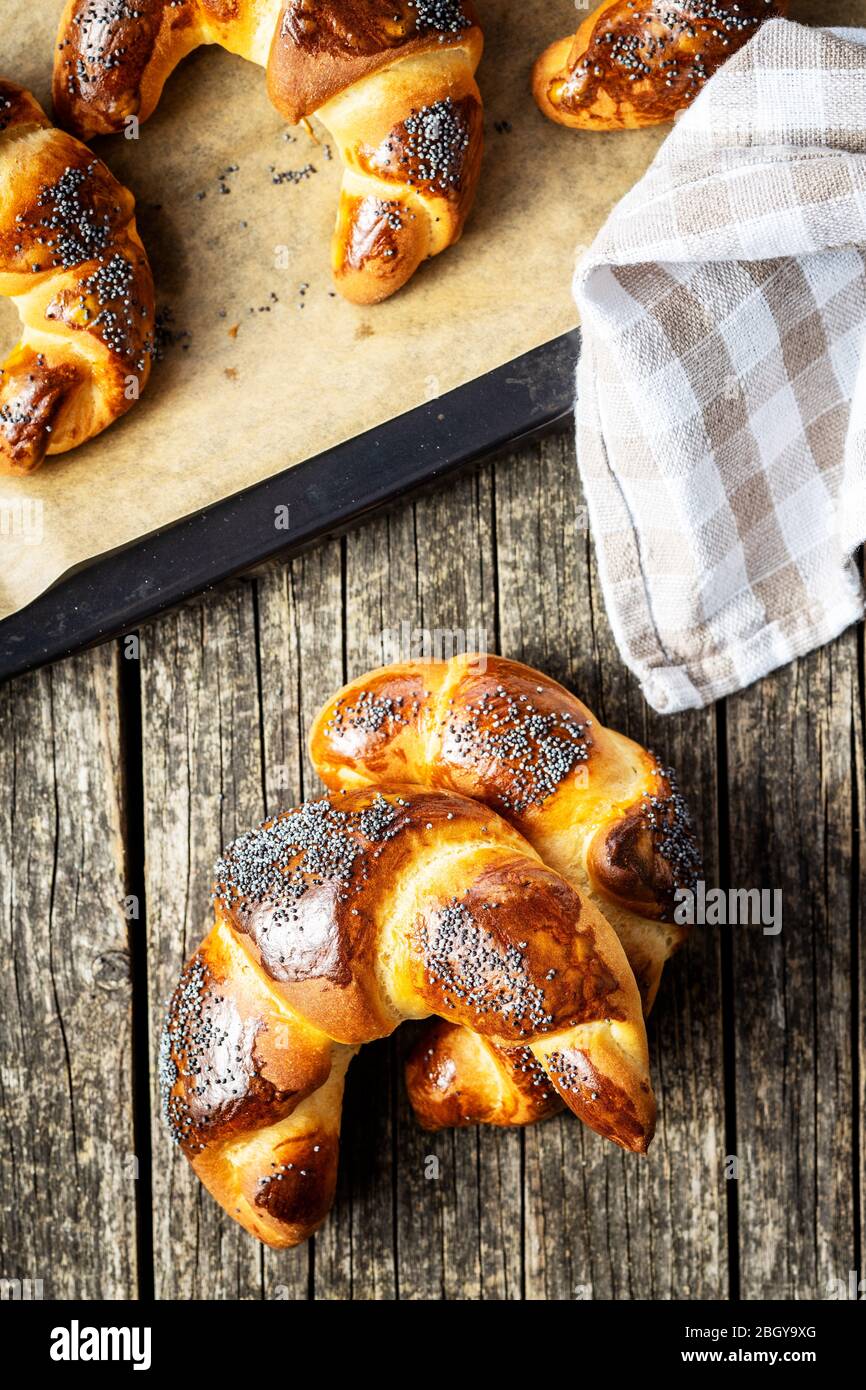 Sweet homemade croissants with poppy on wooden table. Top view. Stock Photo
