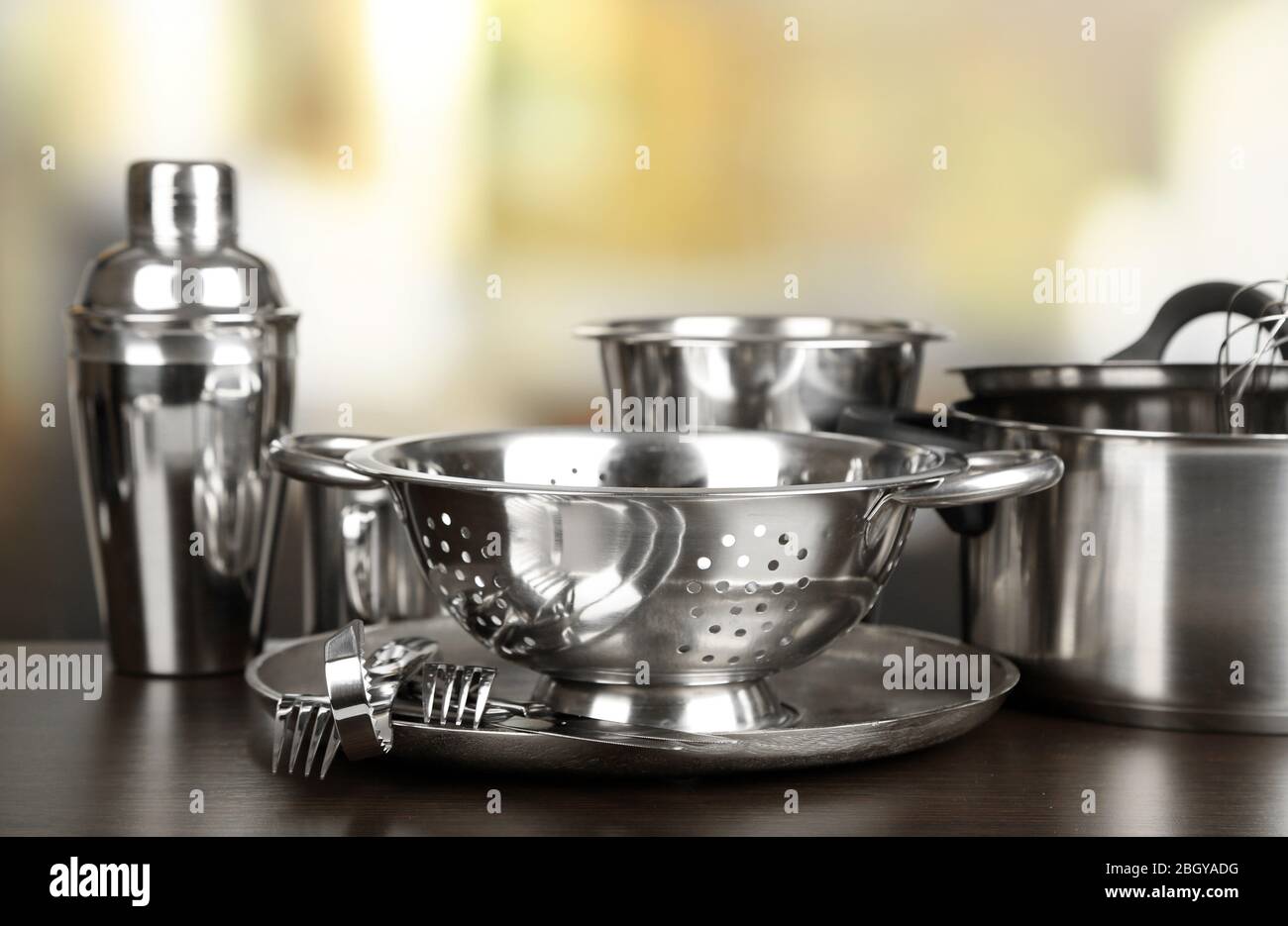 Stainless steel kitchenware on table, on light background Stock Photo ...