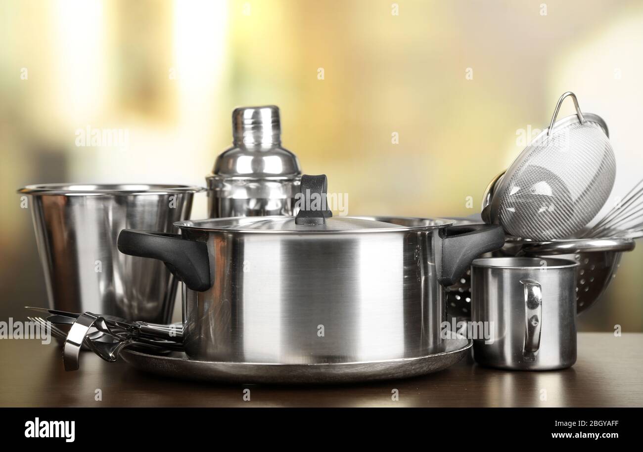 Stainless steel kitchenware on table, on light background Stock Photo ...