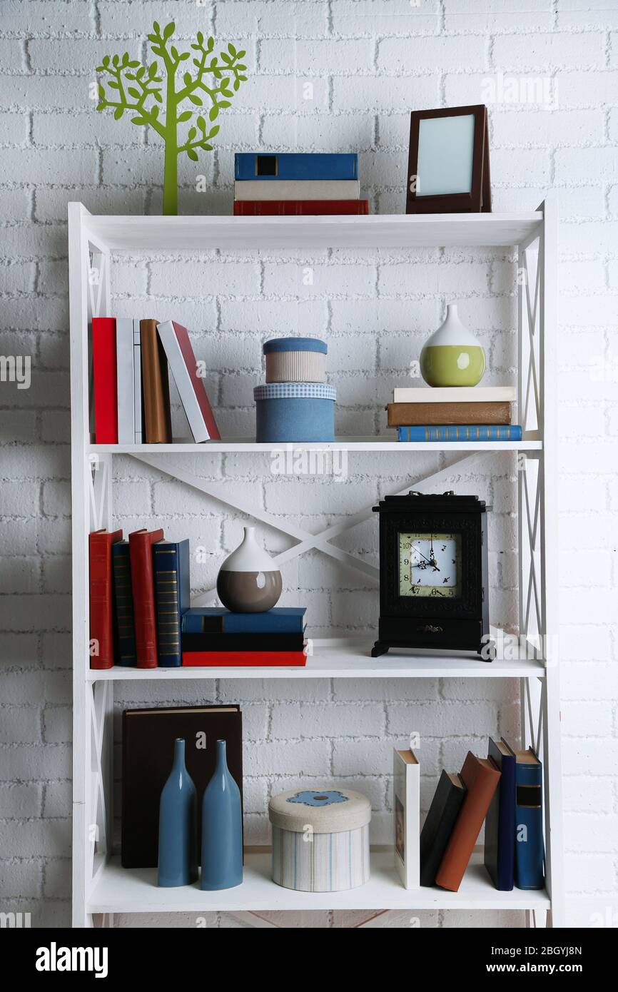 Bookshelves with books and decorative objects on brick wall background ...